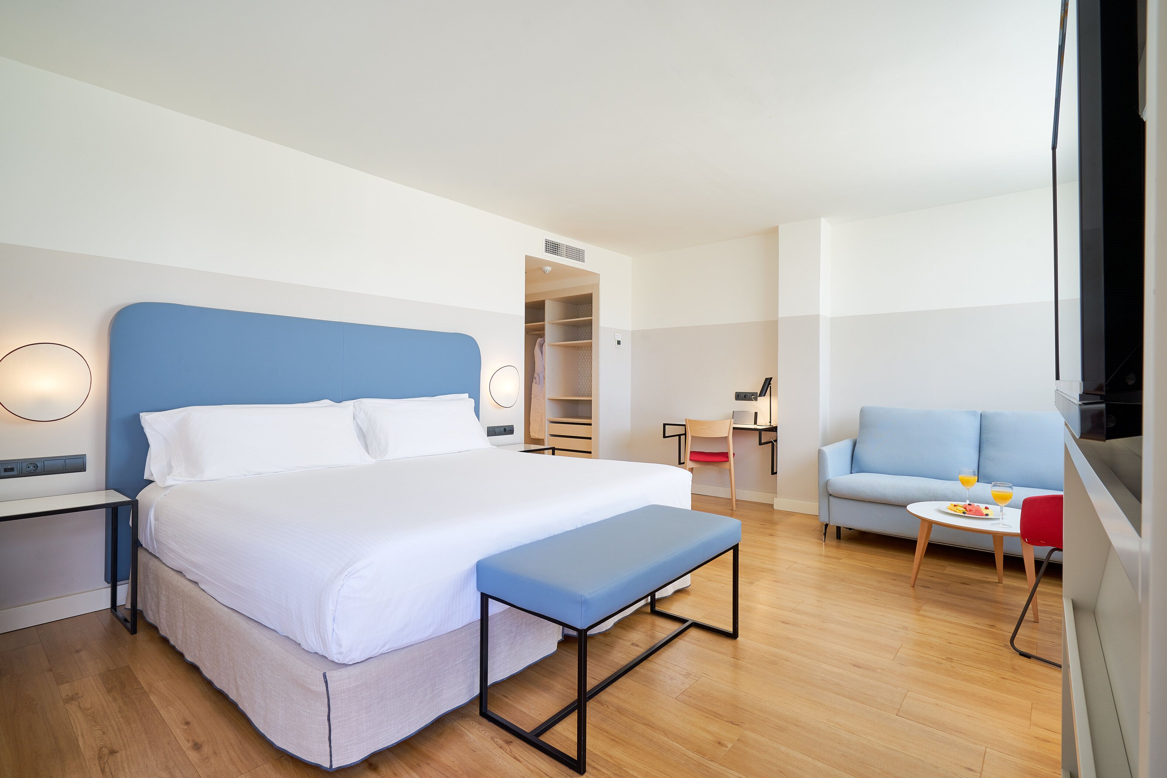 Een moderne hotelkamer met een groot bed, een klein bureau, een bank en een eettafel.