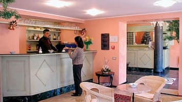 Ein Hotel-Empfangsbereich mit Theke, Bar und Sitzgelegenheiten.