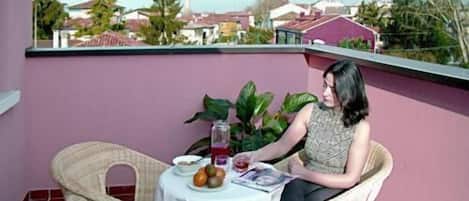 A balcony with a table set for two, a chair, and a potted plant.