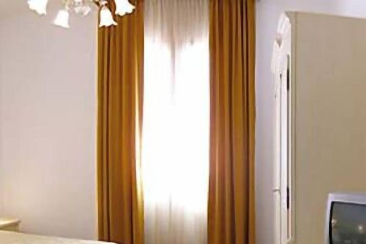 A room with a bed, a television, and curtains.