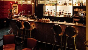 Zona de bar amb sostre vermell, tamborets i una estanteria ben fornida de begudes alcohòliques.