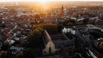 Luchtbeeld van een historische stad met een opvallende kerk, dicht op elkaar gebouwde woonhuizen en een hoge toren.