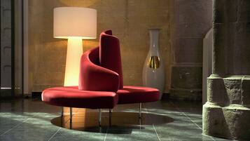 Une chaise rouge moderne dans un hall d’entrée, avec un grand lampadaire et un vase.