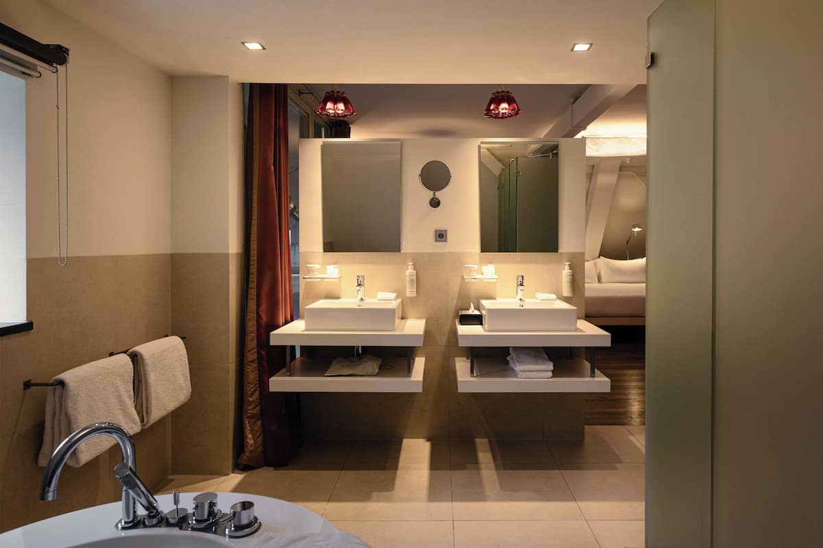 Un baño moderno con dos lavamanos, un espejo y un perchero para toallas.