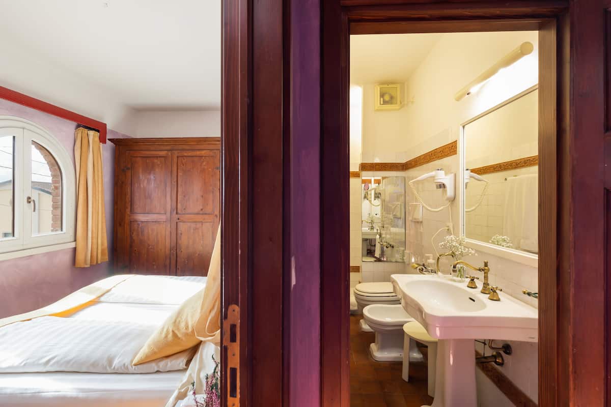 A bedroom with a bed, a wooden wardrobe, and a window with curtains.