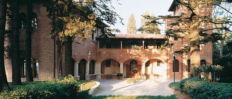 Un edificio histórico con un patio, muros de ladrillo y paseos con arcos.