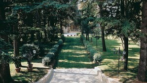 Un vialetto in pietra che si snoda attraverso un giardino curato, con alberi e piante in vaso.