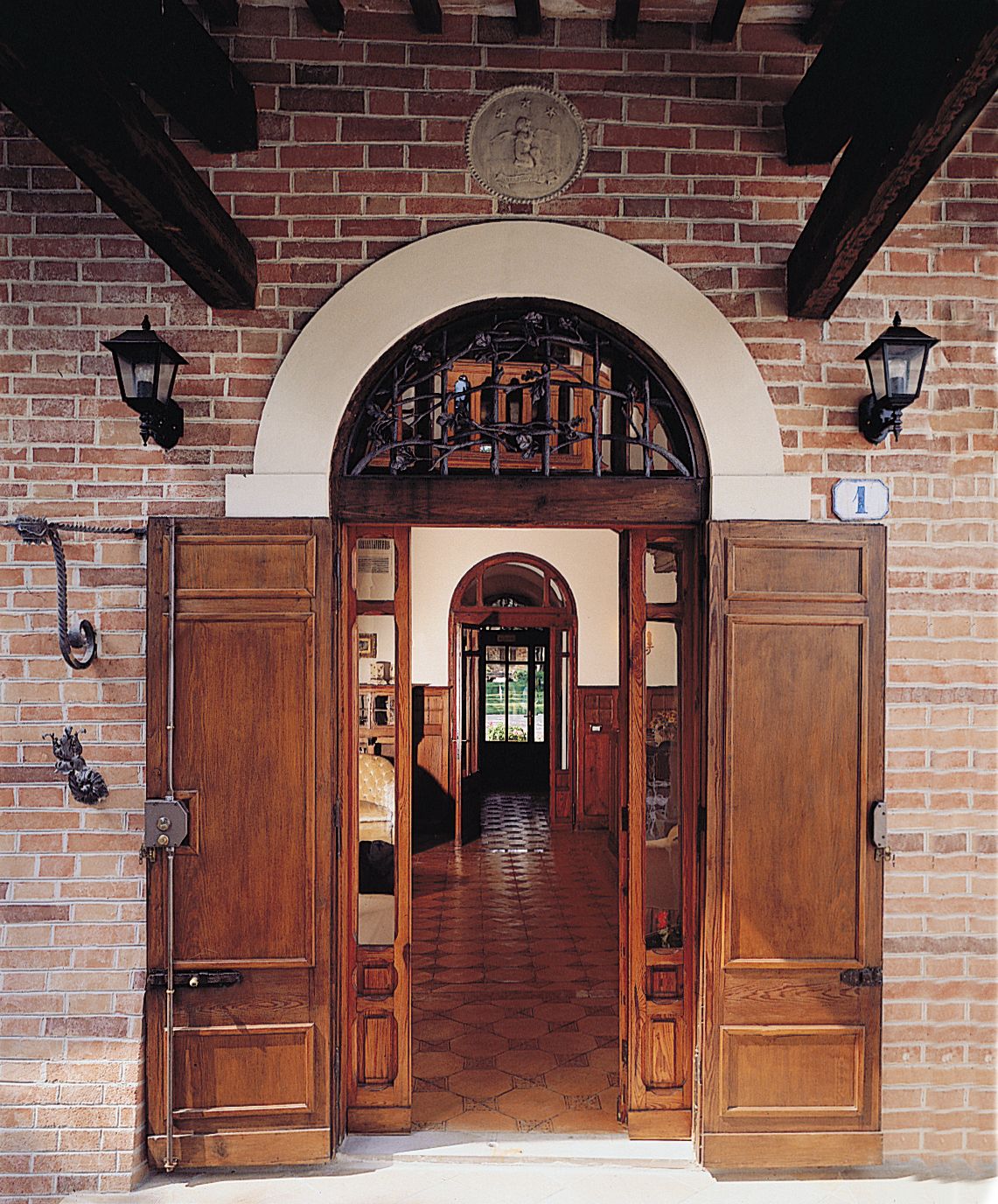 A wooden double door with a brick wall and a brick floor.