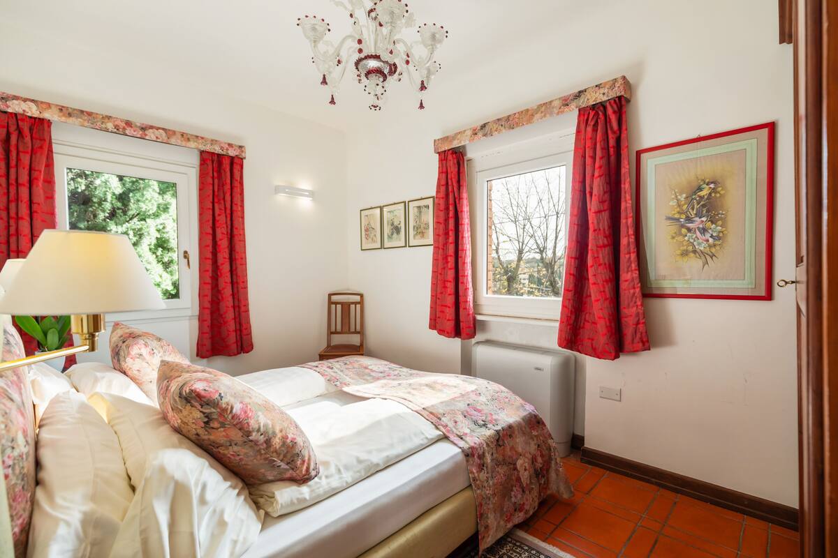 A bedroom with a bed, a lamp, a chair, and a window with curtains.