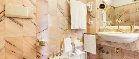 A bathroom with a marble floor, a sink, a bidet, and a mirror.