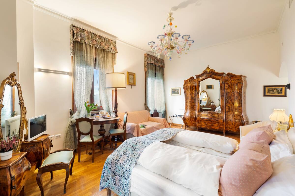 A hotel room with a bed, a desk with a computer, a chair, a dresser, and a mirror.