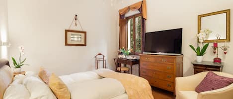 A bedroom with a bed, a desk, a television, a chair, and a dresser.