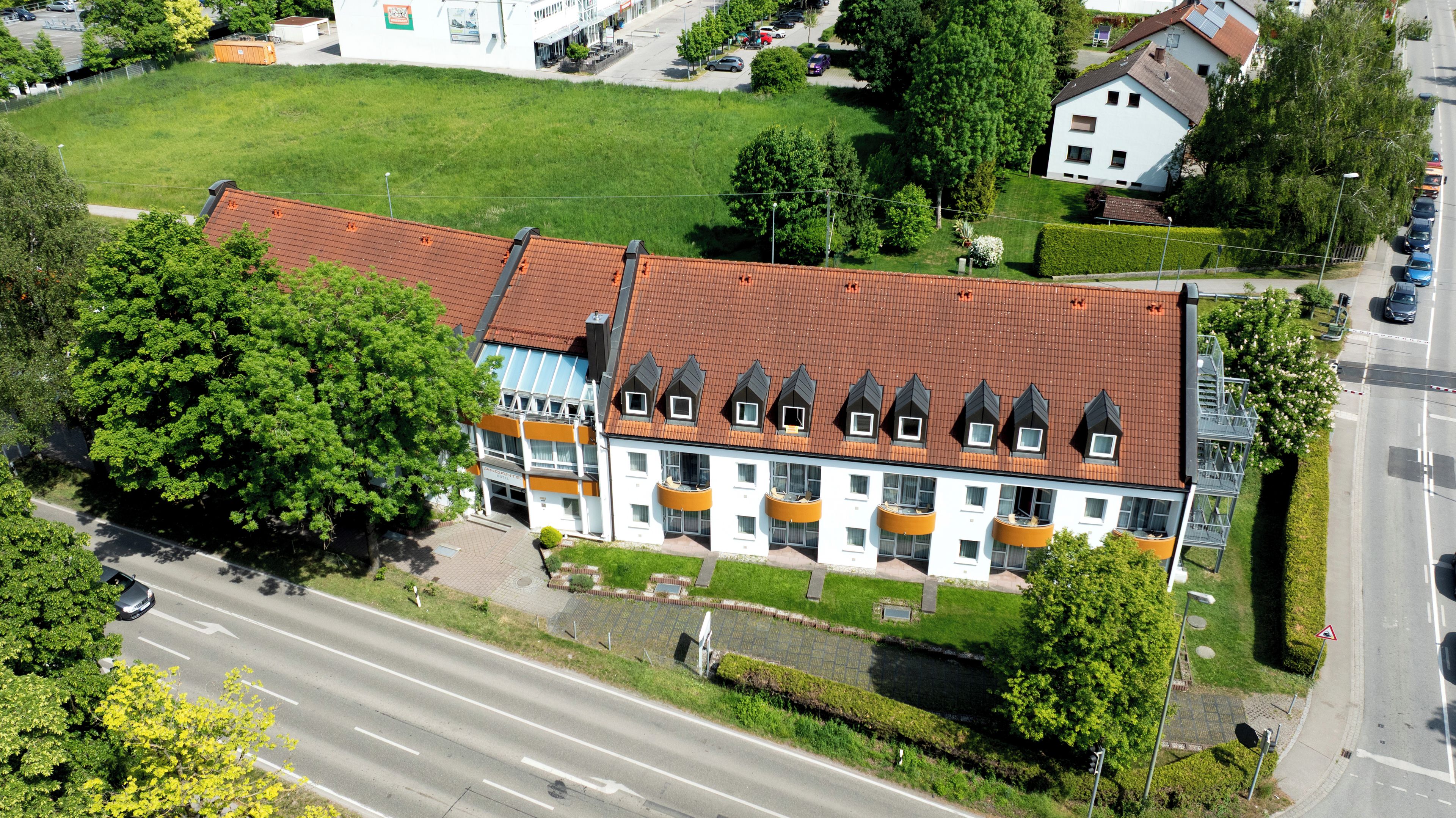 Ein mehrgeschossiges Gebäude mit rotem Ziegeldach, mehreren Balkonen und einem zentralen Innenhof.