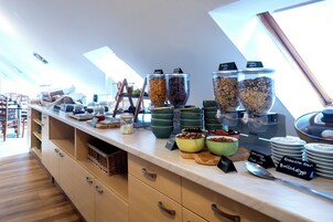 Zona de bufé con distintos alimentos y recipientes.