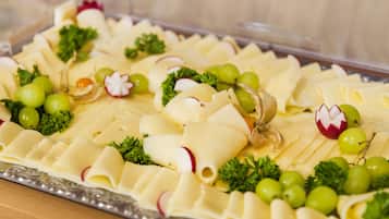 A platter of sliced cheese with grapes and radishes.