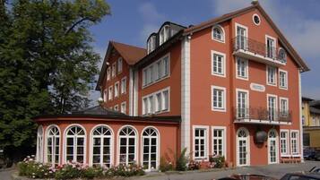 A red and white hotel with a balcony and arched windows.