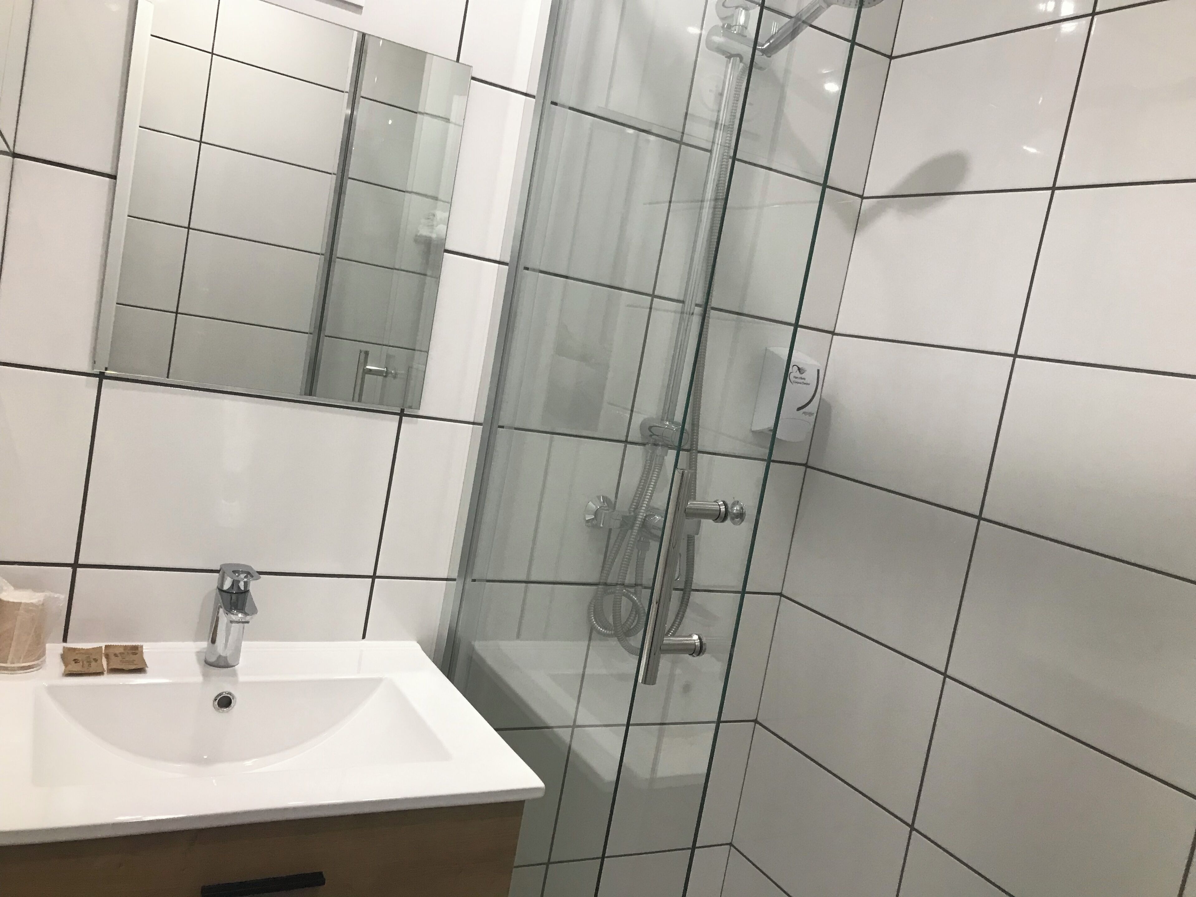 A bathroom with a white sink, mirror, and glass shower enclosure.
