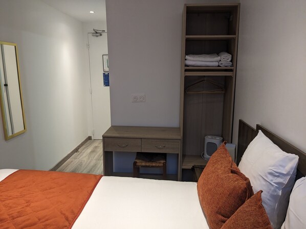A hotel room with a bed, a desk, a wardrobe, and a mirror. - Hotel Morand (Rouen)