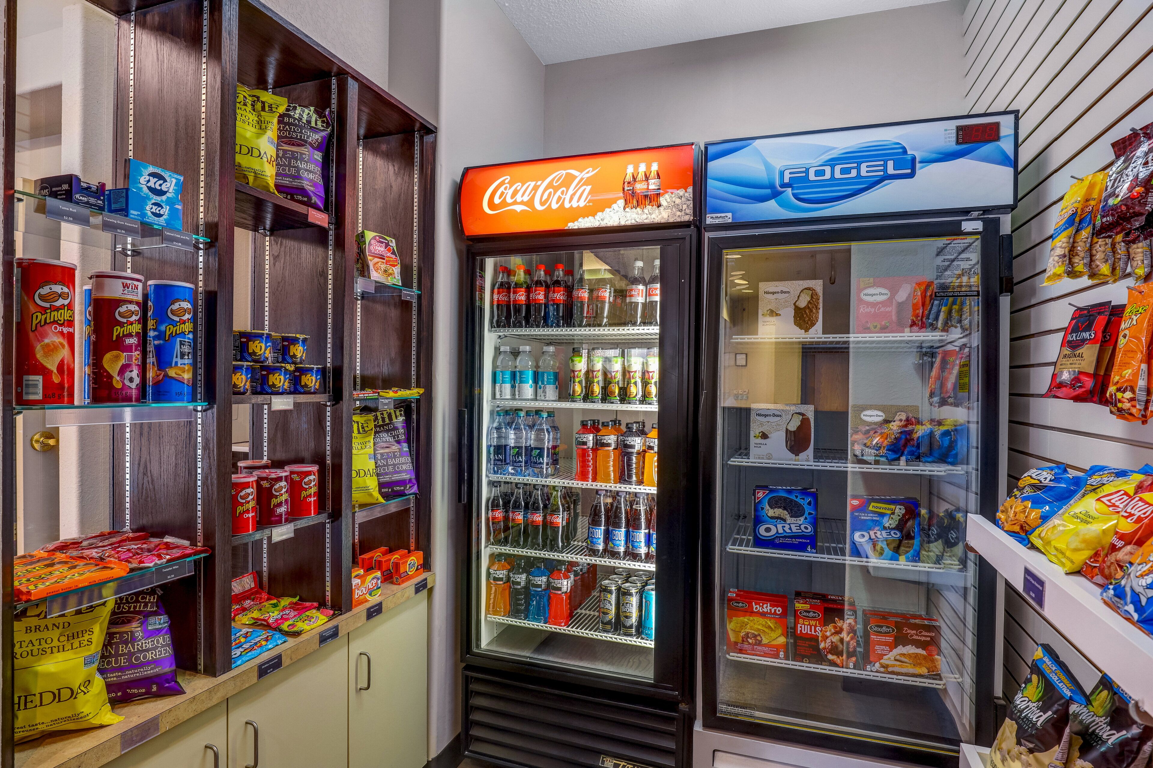 Una máquina expendedora con refrigerios y bebidas, un refrigerador Coca-Cola y un refrigerador Fogel.