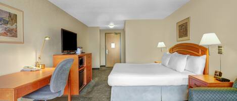A hotel room with a bed, desk, chair, television, and lamps.