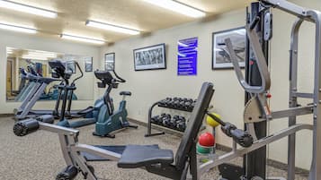 Ein Fitnessraum mit Trainingsgeräten, einem Wandspiegel und gerahmten Bildern.