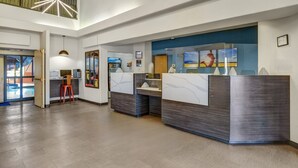 A reception area with a desk, chairs, a glass partition, and artwork on the walls.