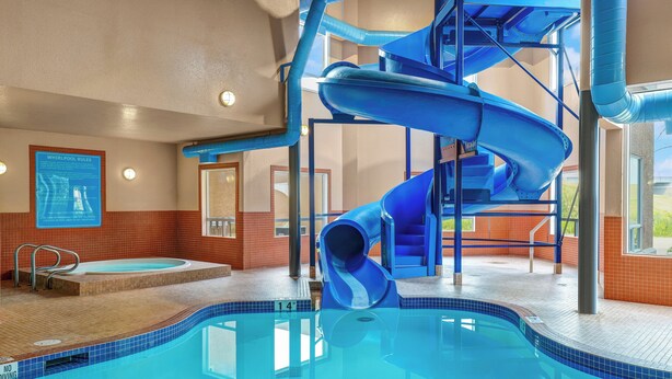 An indoor swimming pool with a blue water slide and a hot tub.
