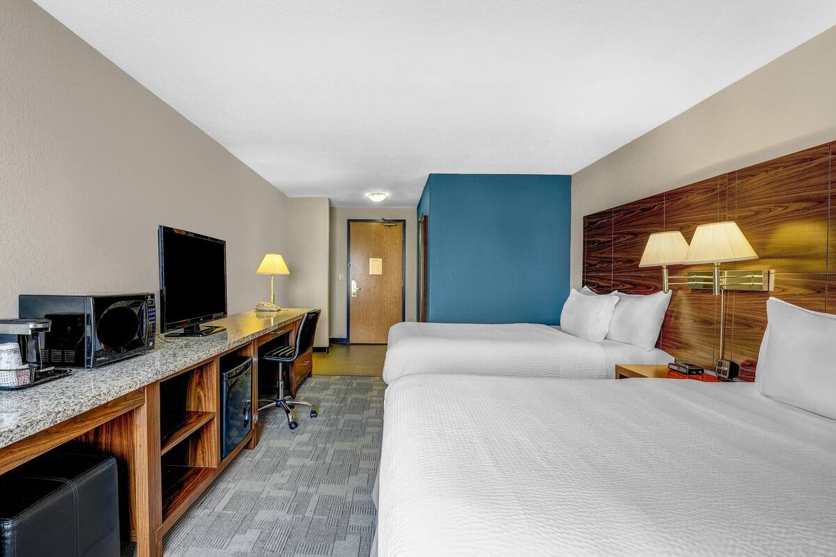 Ein Hotelzimmer mit Bett, Schreibtisch mit Fernseher, Lampe und Mikrowelle.