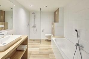 A modern bathroom with a large bathtub, a separate shower area, and a toilet.
