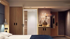 Una habitación de hotel moderna con una cama grande, un armario de madera, un tocador con espejo y un jarrón decorativo con flores.