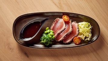 A plate with sliced meat, vegetables, and a sauce.