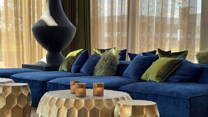Una sala de estar moderna con un sofá seccional azul, mesas auxiliares de madera hexagonal y una lámpara de pie negra grande.