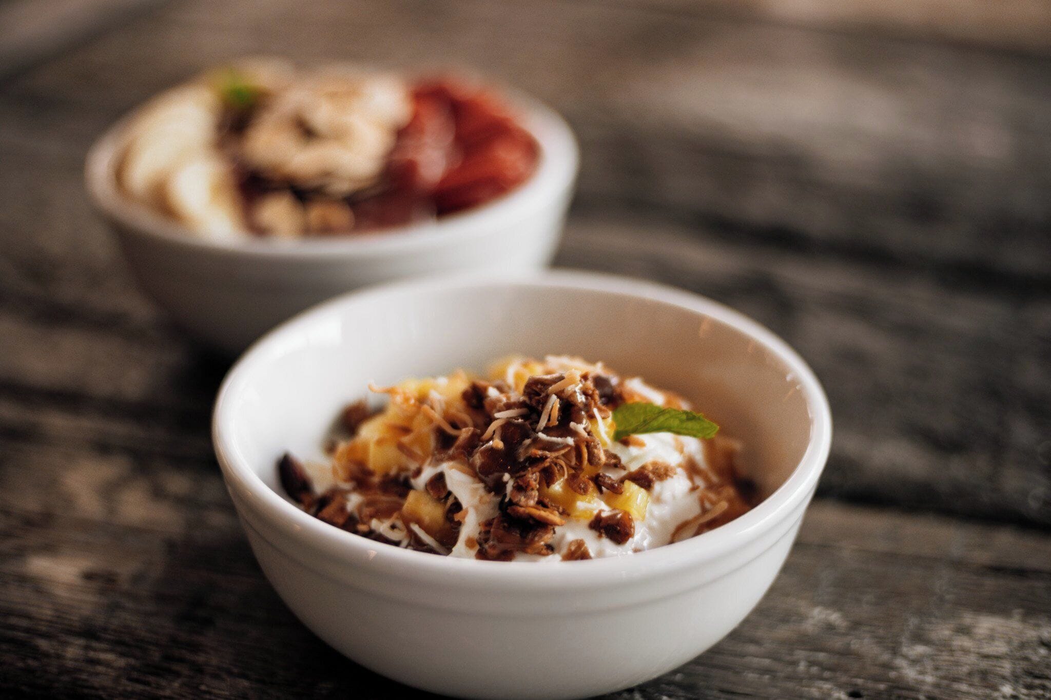 Two bowls of food on a wooden surface.