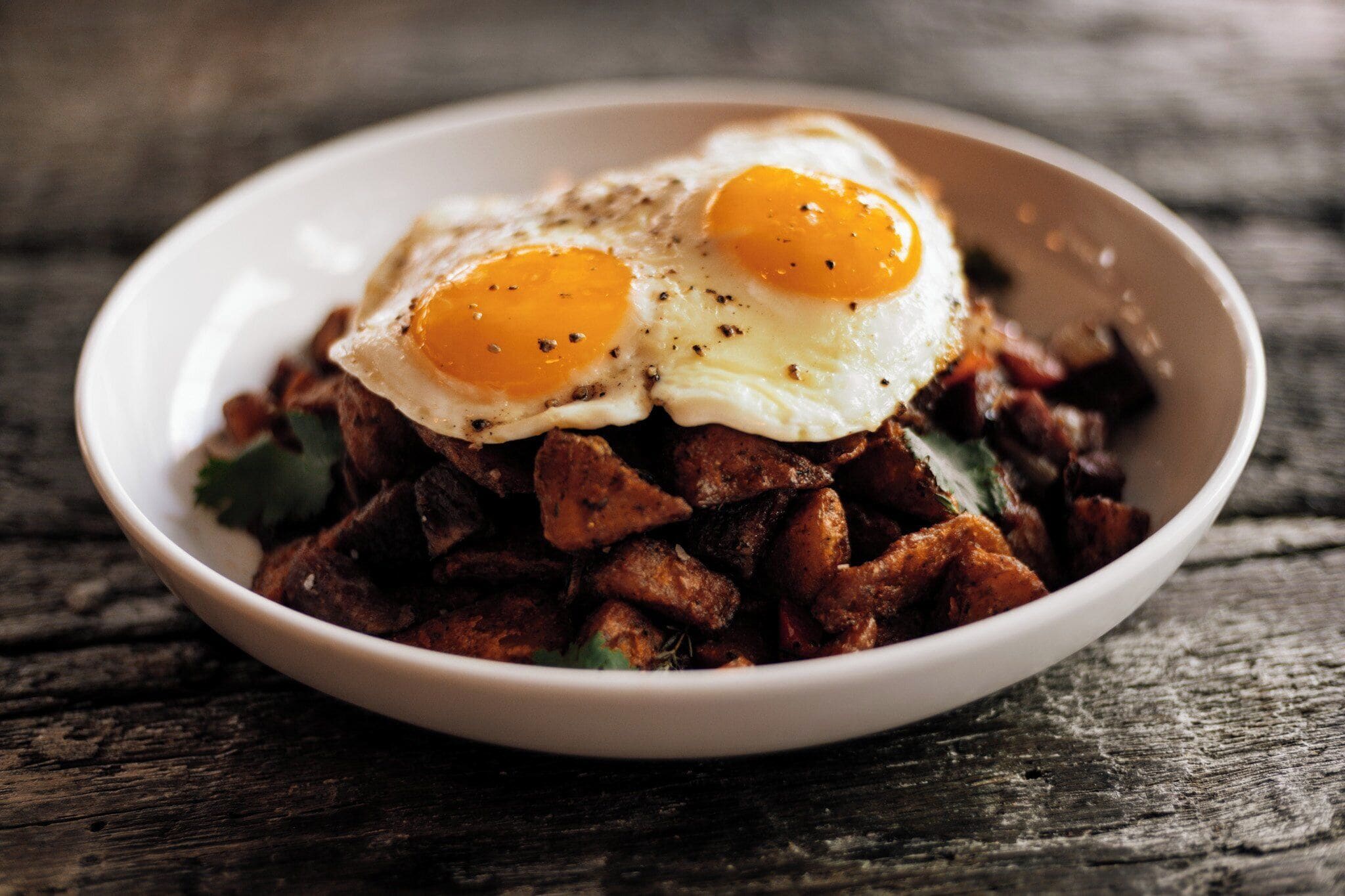 Un plato de comida con dos huevos fritos sobre una mesa de madera.
