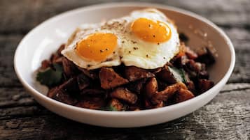 Un plato de comida con dos huevos fritos sobre una mesa de madera.
