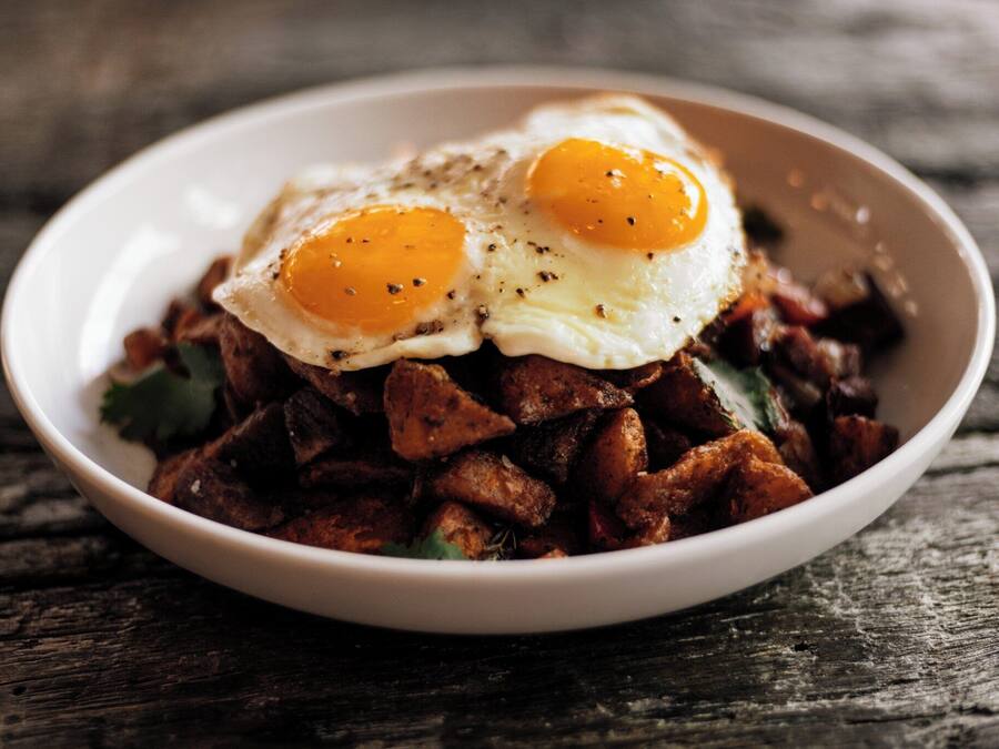 Un plato de comida con dos huevos fritos sobre una mesa de madera.