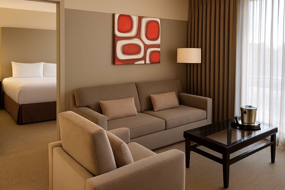 A hotel room with a bed, a sofa, a coffee table, and a lamp.