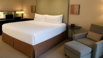 A hotel room with a large bed, a desk, a chair, and a small table.