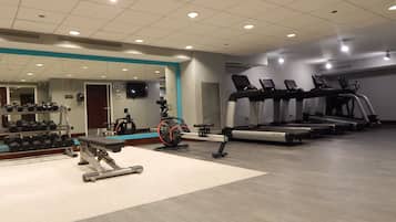 A gym with treadmills, elliptical machines, and dumbbells.