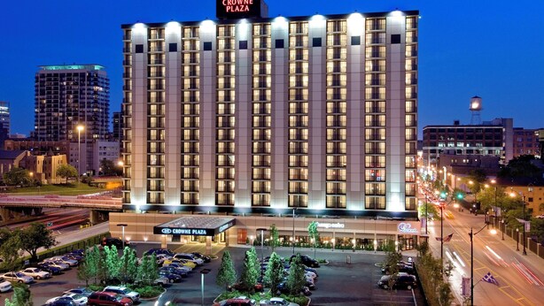 Un hôtel à plusieurs étages, reconnaissable à son grand panneau indiquant « Crowne Plaza ».