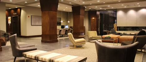 A spacious lobby with a seating area, a reception desk, and a large screen.