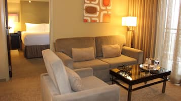 Quarto de hotel com sofá, mesa de centro, abajur e um quadro na parede.