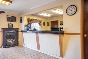 A reception area with a fireplace, a clock, and a counter. - Econo Lodge Inn & Suites Windsor Locks Bradley Airport (Windsor Locks)