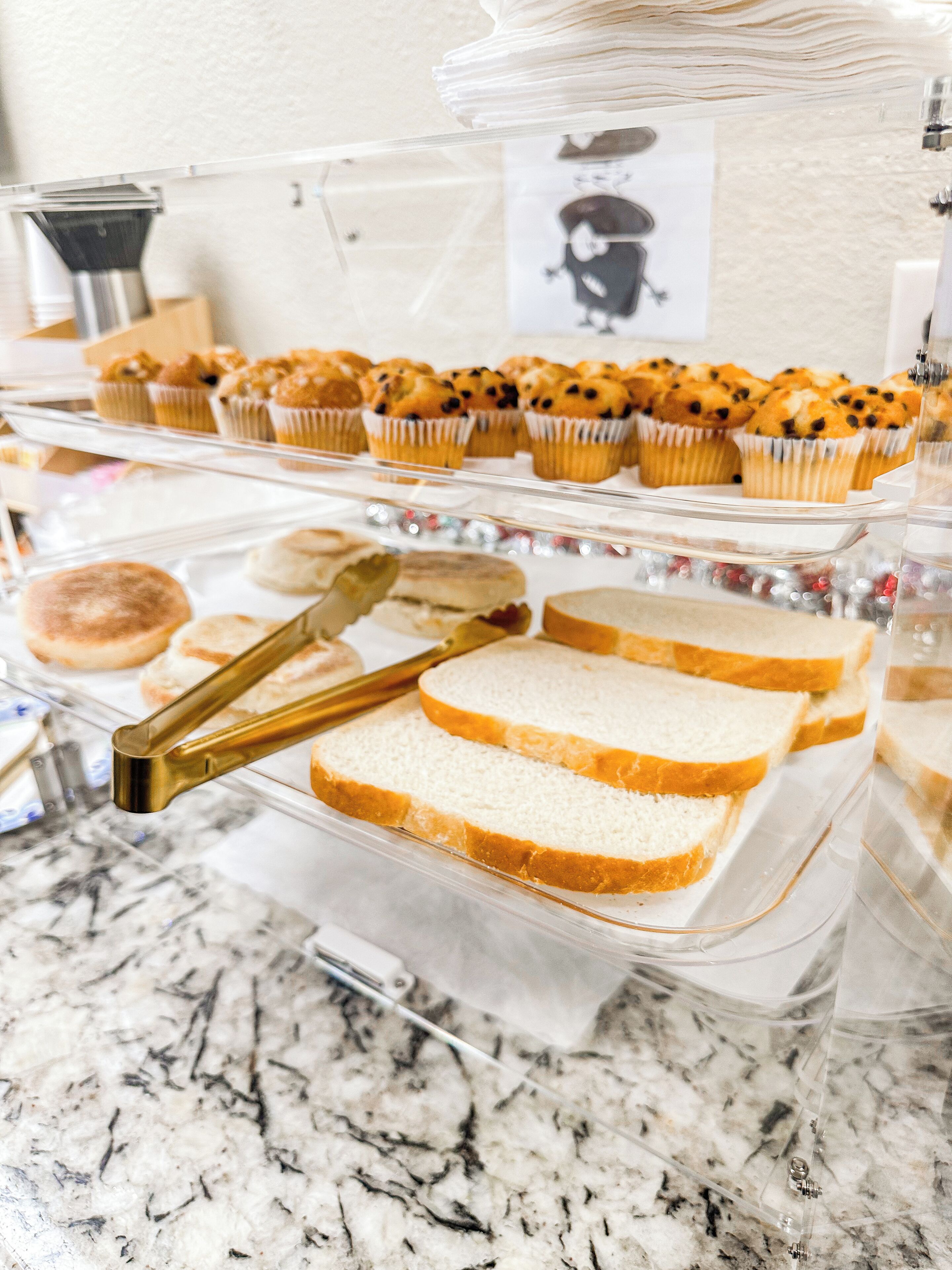 Une vitrine de boulangerie présentant des muffins et du pain tranché.