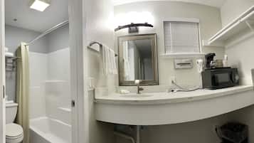 A bathroom with a toilet, shower, sink, and a mirror.