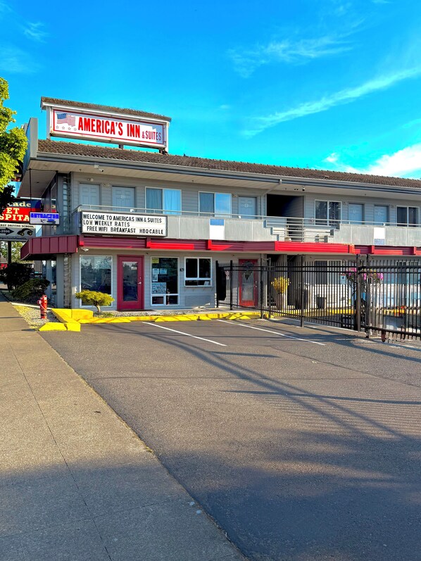 A motel with a sign for 'America's Inn & Suites' offering low weekly rates, free WiFi, breakfast, and HBO cable.