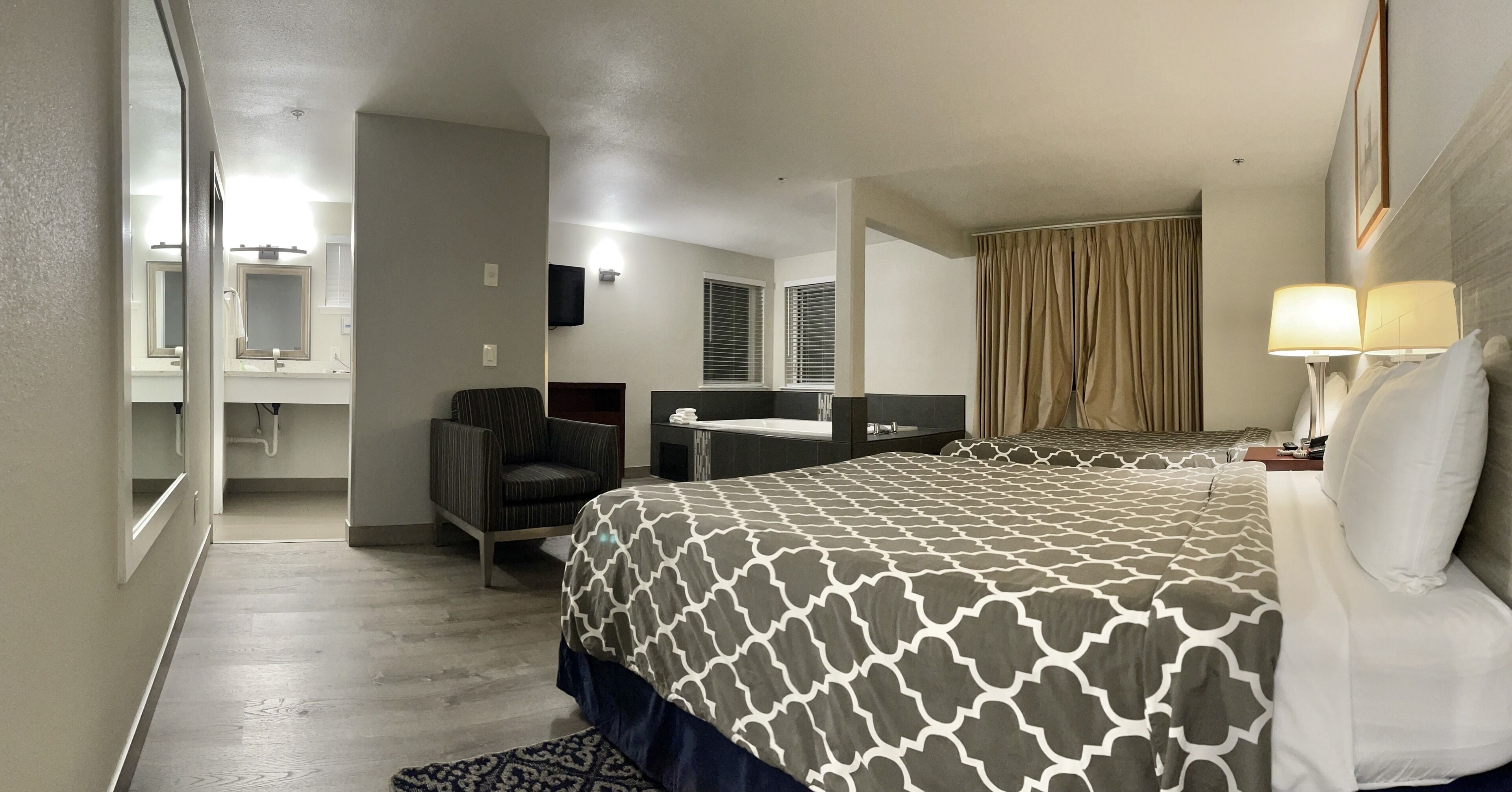 Habitación de hotel con una cama grande, una silla, un escritorio, un baño y una ventana con cortinas.