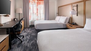 Habitación de hotel con dos camas, un escritorio, una silla, un televisor y una ventana con cortinas.
