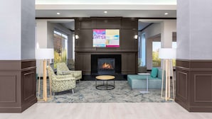 A modern living room with a fireplace, two armchairs, a round coffee table, and a sofa. - Hilton Garden Inn Tulsa South (Tulsa)