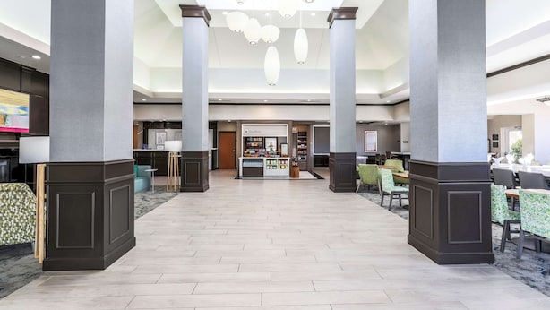 A spacious lobby with high ceilings, large columns, and a central counter area. - Hilton Garden Inn Tulsa South (Tulsa)